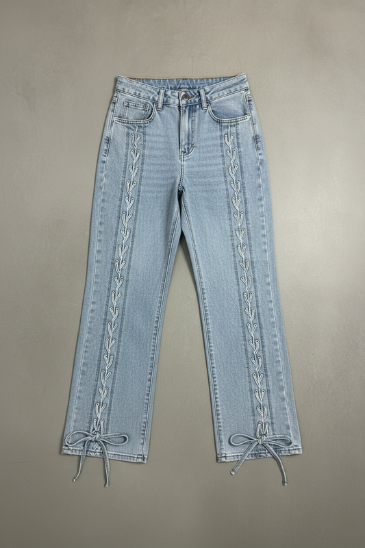 Jeans mit Schnürung vor Betonwand